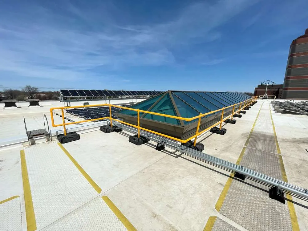 Yellow portable guardrail system set up on commercial rooftop for OSHA compliance.