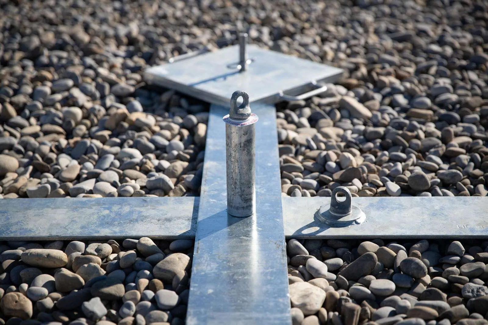 Detailed view of mobile anchor base positioned on gravel-covered rooftop surface.