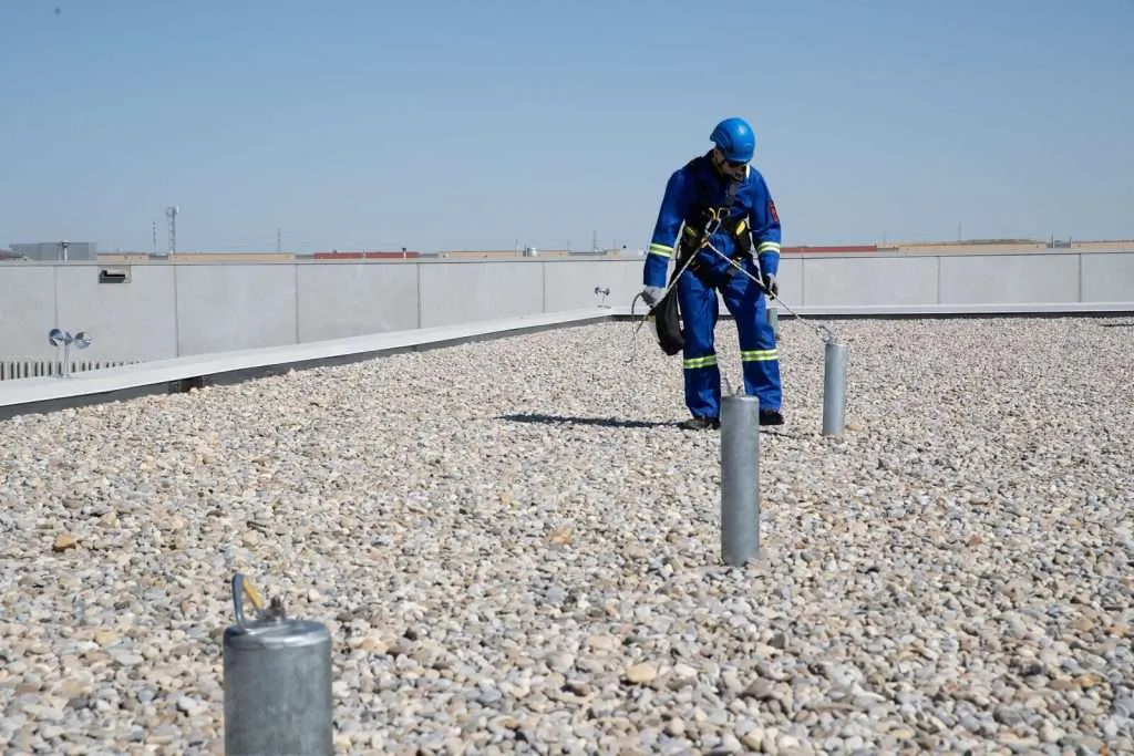 OSHA-compliant rooftop tieback anchor securing horizontal lifeline system.