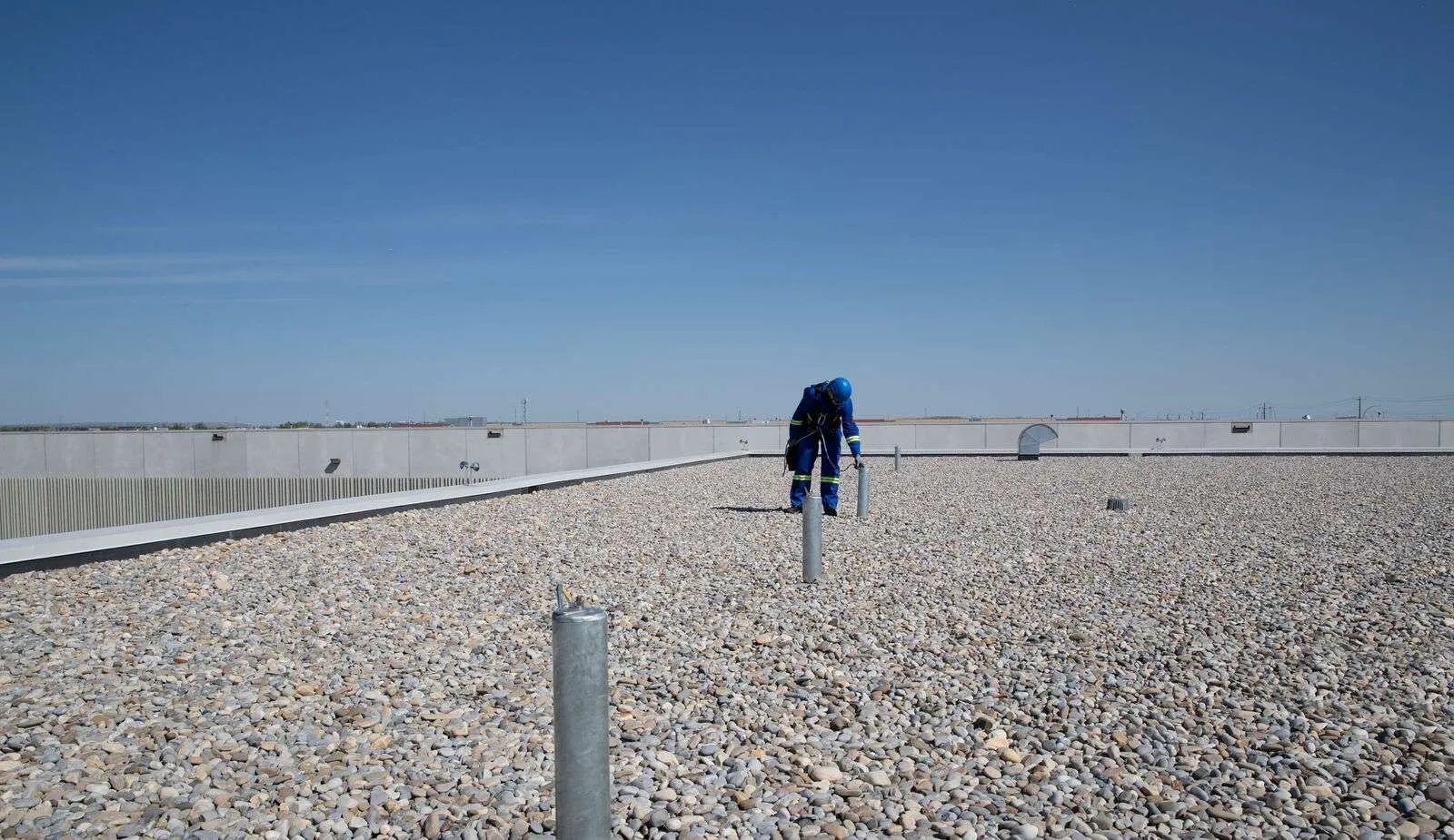 Worker attached to permanent tieback anchor ensuring OSHA-compliant rooftop safety.